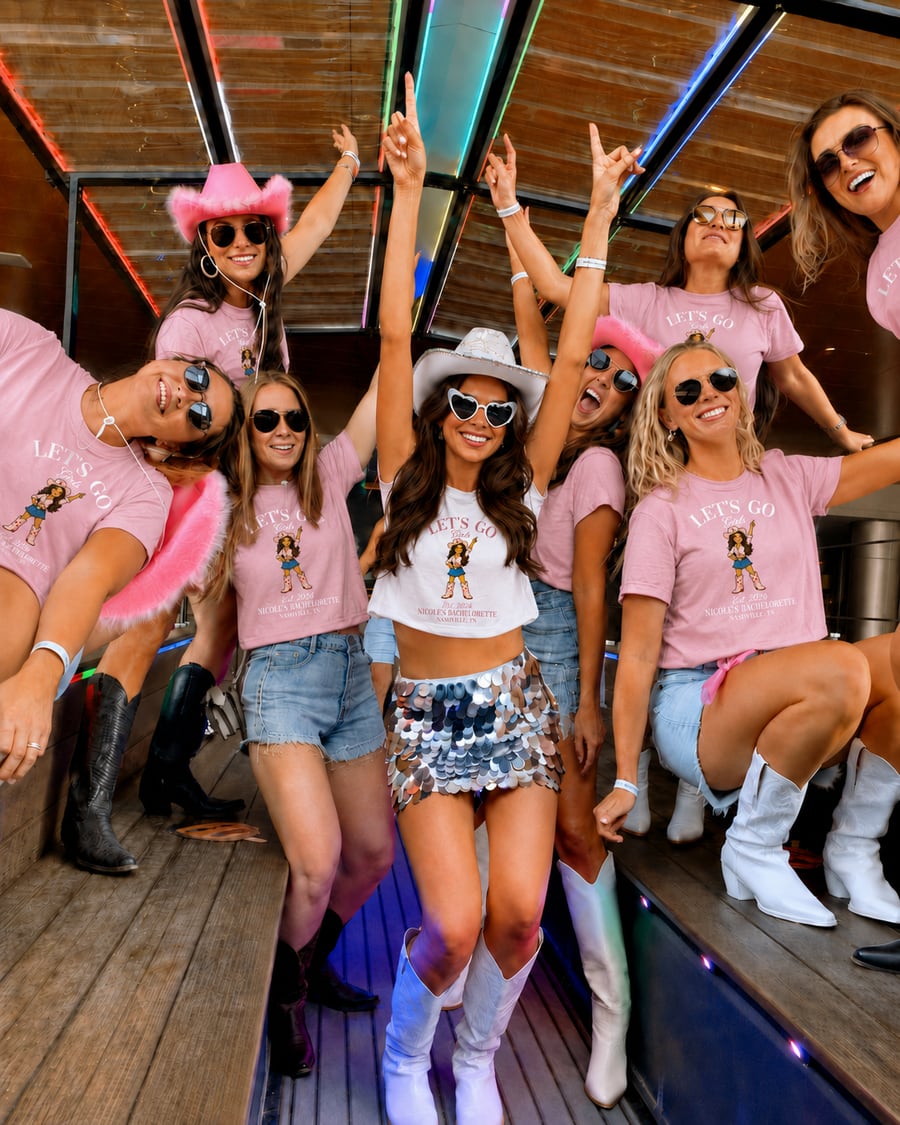 A bachelorette group on a party bus wearing the finished Let's Go Girls shirt
